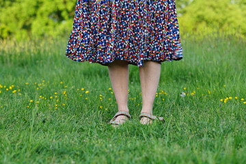 Woman with flower skirt close up bare legs in gras spring summer 