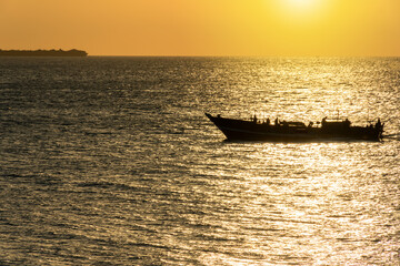 fishing dhow on the open ocean at sunrise sunset - obrazy, fototapety, plakaty