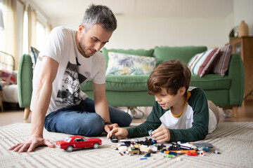 Dad and son spend time together playing games at home. Happy parenting and a good relationship