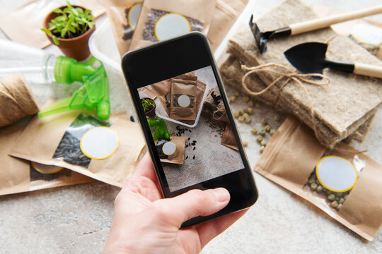 Girl takes pictures  microgreen seeds in paper bags and equipment for sowing microgreens on a smartphone.