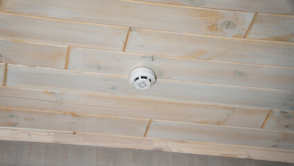 Smoke, fire detector. Close up smoke detector on a ceiling. Wooden ceilling. Fire protection.