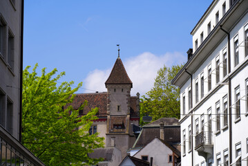 Old town of Basel with facades of historic houses and stone tower on a blue cloudy spring day. Photo taken April 27th, 2022, Basel, Switzerland.