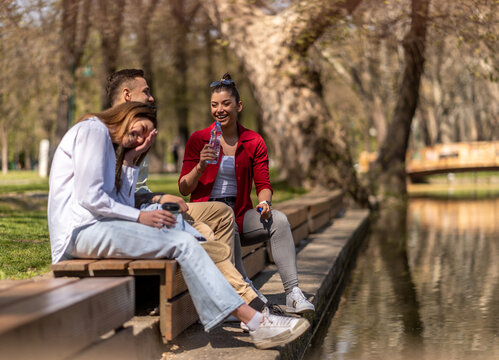 Three friends chillin near the park lake while drinking coffee to go