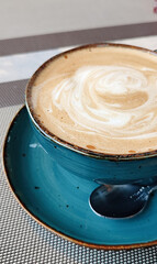 Side view of hot latte coffee in a ceramic blue cup with spoon