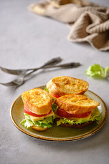 Three fresh sandwich from fried bread, cheese, tomatoes and salad iceberg on a plate on a gray background