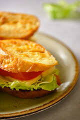 Three fresh sandwich from fried bread, cheese, tomatoes and salad iceberg on a plate on a gray background