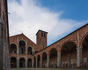 Fototapeta premium Saint Ambrogio church brick building with bell towers, courtyard, arches at overcast day, Milan, Lombardy, Italy