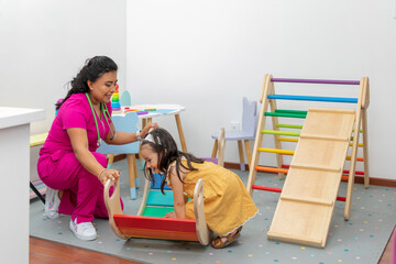 Pediatric doctor with a girl playing in the recreational area of her office