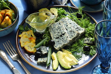 Cheese with avocado, olives and cauliflower on a blue plate