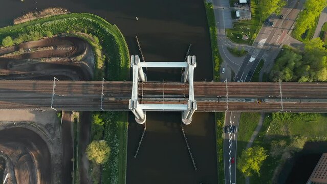 NS Intercity Materieel Crosses Railway Bridge Spanning Gouwe Canal With Traffic In The Road In Netherlands. - aerial