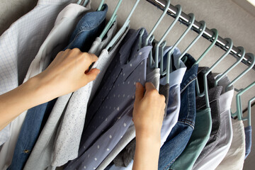 A woman chooses clothes on a hanger.