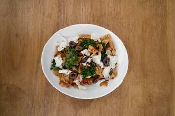 Pasta dish. Top view of a plate with pappardelle noodles, pesto, almonds, kale, burrata cheese and...