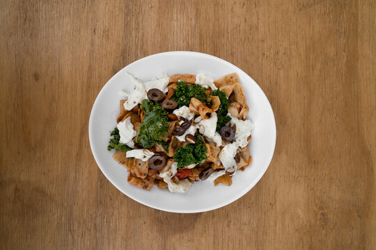 Pasta Dish. Top View Of A Plate With Pappardelle Noodles, Pesto, Almonds, Kale, Burrata Cheese And Tomatoes, In The Restaurant Wooden Table. 