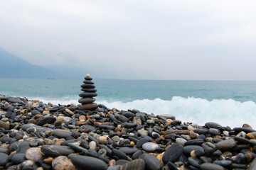 stacked stones, tower or pyramid of stones on the beach, balance, Sea waves background （Hualien, Taiwan）