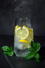 Refreshing cocktail on a black background. Soft drink with ice and lemon. cold drink