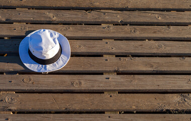 Obraz na płótnie Canvas a white hat with a black band lying on the ground on a pier on a Spanish beach
