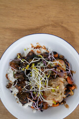 Vegan cuisine. Gluten free. Closeup view of a bowl with grilled tofu, soy sprouts, pumpkin seeds, season vegetables, spicy mango, sushi rice, cucumber and kimchi.	

