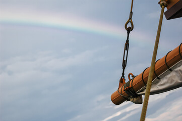crane hook, wooden rigging of a sailing boat on blue sky with the rainbow in the foreground