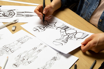 The illustrator draws sketches of robot computer game characters. The artist creates a design of...
