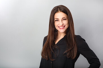 Fototapeta premium Beautiful young business toothy smiling woman thinking and looking happy on blue grey background with empty copy space. Portrait