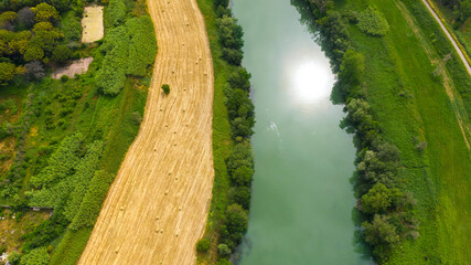 Aerial view of a river with a cultivated wheat field alongside it.