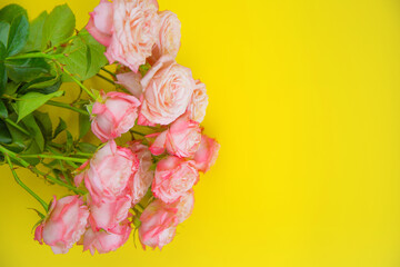A large bouquet of pink roses lies on a yellow background with a place for text. High quality photo