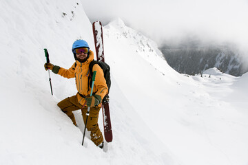 happy male skier with skitour equipment is climbing the snowy hill