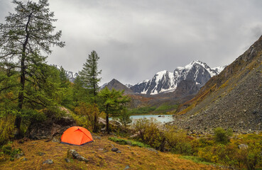 Bad weather on a hike, camping in the rain. Morning rain and fog near a mountain lake, Shavlin lake Altai, a tent camp in the fog.