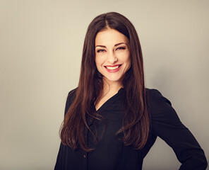 Obraz premium Beautiful young business toothy smiling woman thinking and looking happy on blue grey background with empty copy space. Portrait