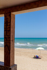 tourists enjoy a sunny day lying on a towel on a Spanish beach under an umbrella