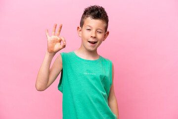 Little caucasian boy isolated on pink background showing ok sign with fingers