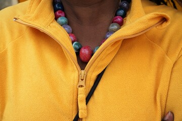 Dekolletee von Afrikanischer Frau mit bunter Halskette und gelbem Pullover 