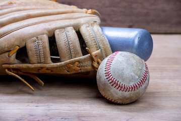 Vintage classic leather baseball glove and baseball bat isolated on wooden table.