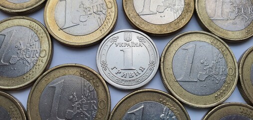 One hryvnia coin surrounded by a large number of one euro coins close-up