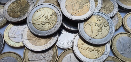 One hryvnia coin surrounded by a large number of two and one euro coins close-up