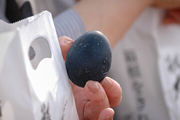 a hand holds a strange Japanese black egg
