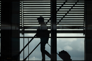 silhouette of tourists with suitcases walking in an airport transfer with blinds in the background
