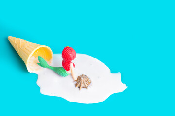 Fototapeta premium Mermaid figurine in melted ice cream on blue