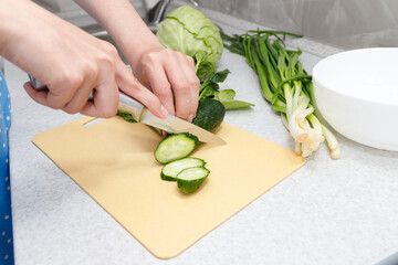 cut a cucumber for salad with a knife. close-up