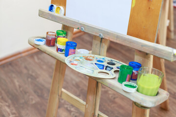 paints of the artist on an easel in a clase