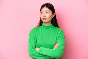 Young Chinese woman isolated on pink background keeping the arms crossed