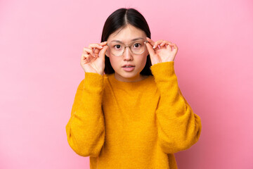 Young Chinese woman isolated on pink background With glasses and frustrated expression
