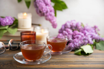 A cup of green tea against the background of a spring bouquet of lilacs . Romantic composition with books and candles. spring tea drink. Place to copy. Romantic concept.