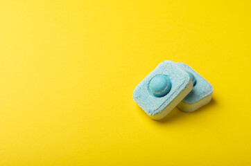 Tablets for softening water on a yellow background. Capsules for washing machines and dishwashers, preventing limescale. Place to copy.