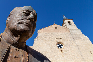 Obraz premium Low Angle View of Bronze Clergy Statue in Front of Spanish Church Architecture