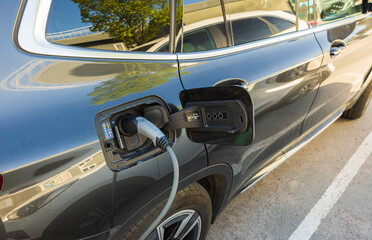 Close up view of connected charging cable to black car from an electric vehicle charging station. Sweden.