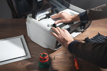 Caucasian man repairing digital printer.