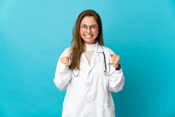 Middle age Brazilian doctor woman isolated on blue background celebrating a victory in winner...