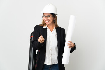 Middle age architect woman with helmet and holding blueprints over isolated background making money gesture
