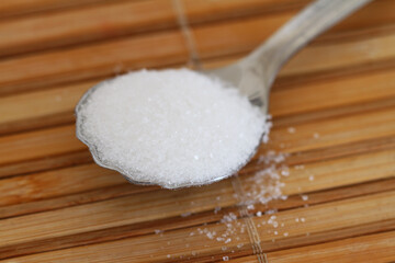 Spoonful of sugar on bambook mat, closeup
